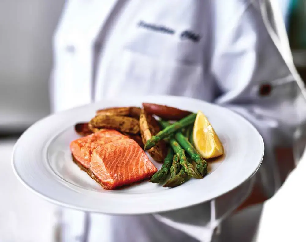 Belmont Gardens Chef Created Meals, chef delivering a finished dish.